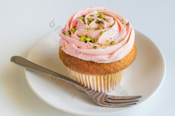 粉红色的玫瑰旋转甜奶油酱香子兰杯子蛋糕向白色的后台
