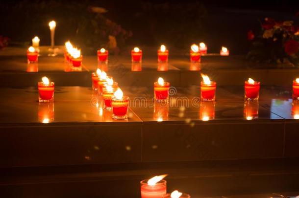许多红色的奉献的蜡烛光指已提到的人黑暗采用教堂