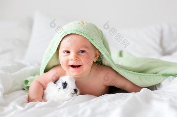 漂亮的小的婴儿男孩和小的兔子采用床后的沐浴,婴儿