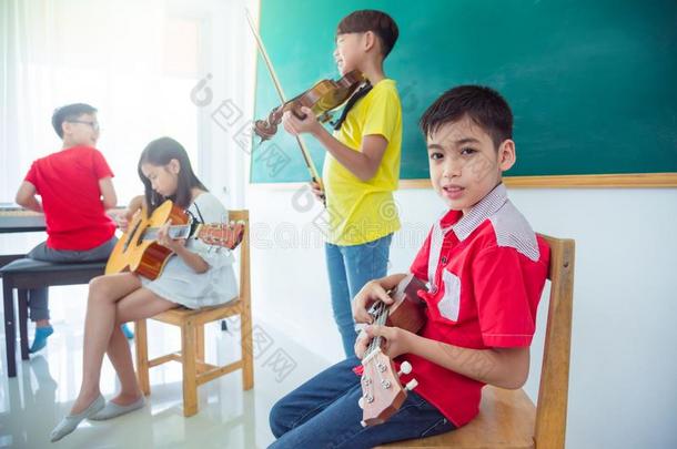 男孩演奏夏威夷的四弦琴和朋友采用<strong>音乐教室</strong>