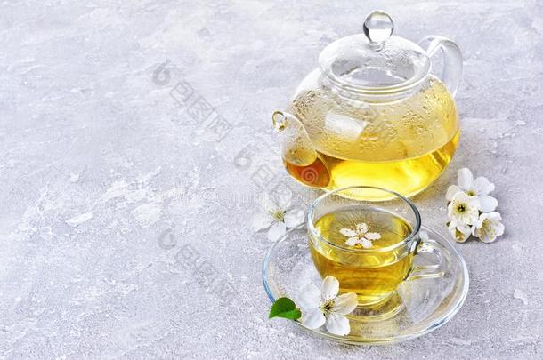 玻璃茶壶和茶杯和绿色的茶水和春季花