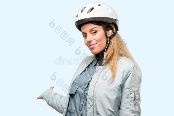 年幼的女人和自行车头盔和耳机越过蓝色背景