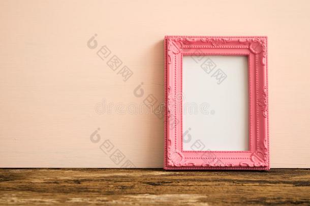 粉红色的酿酒的照片框架向老的木制的表越过粉红色的墙背