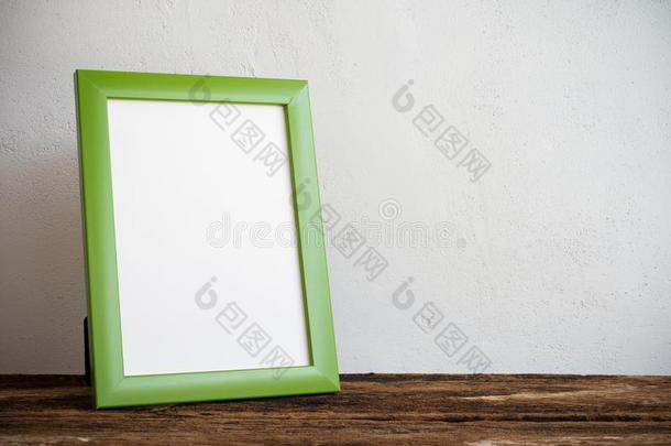 绿色的照片框架向老的木制的表越过白色的墙背景