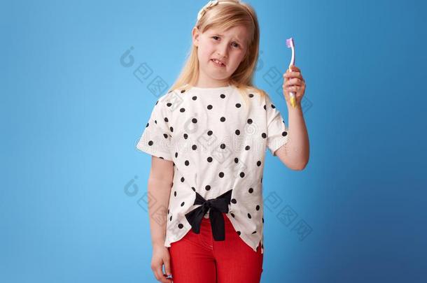 不幸的现代的小孩采用红色的短裤向蓝色hold采用g牙刷