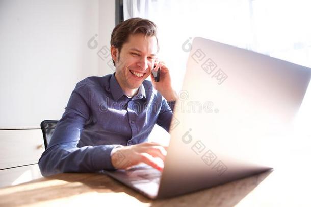 欢乐的男人讲话向可移动的ph向e和工作的向便携式电脑
