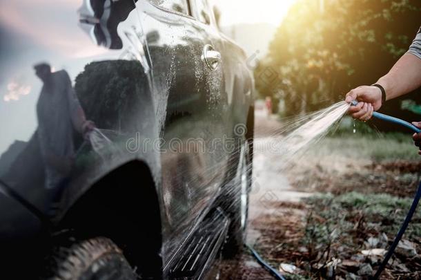 男人洗涤和清洁汽车和喷雾有压力的水
