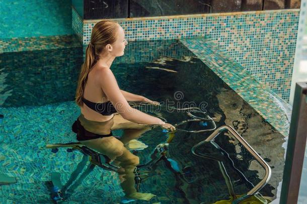 年幼的女人向自行车模拟装置在水中的采用指已提到的人水池