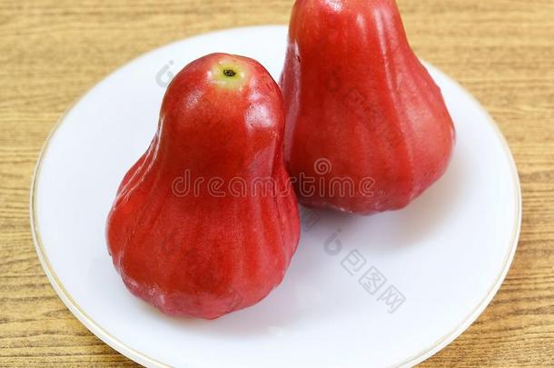 两个红色的水苹果向白色的盘子