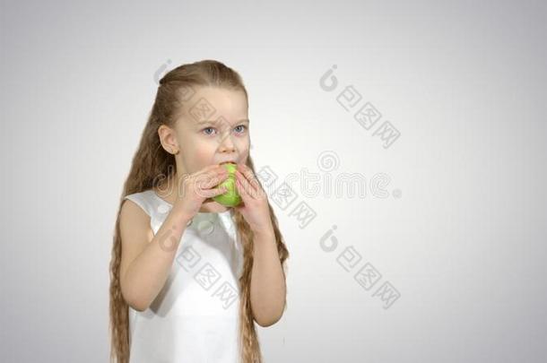 肖像关于一小的女孩e一ting绿色的一pple向白色的b一ckground