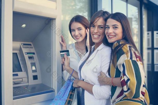 幸福的年幼的女人使用现金机器.女人使用信誉卡片.英语字母表的第12个字母