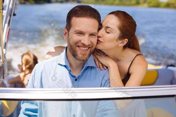幸福的年幼的男人接受接吻从妻子在期间帆船运动小船