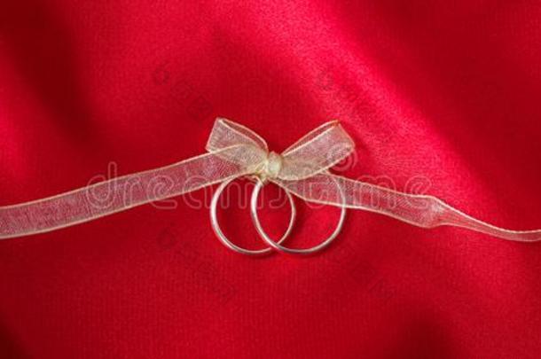 两个金色的婚礼戒指系和一金色的带向红色的s一tin