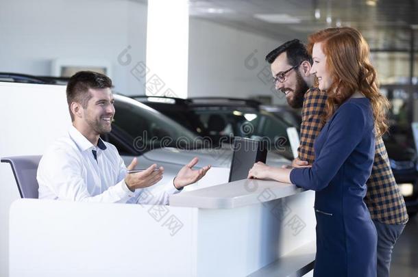 微笑的汽车卖者讲话和幸福的买主采用专用的秀洛