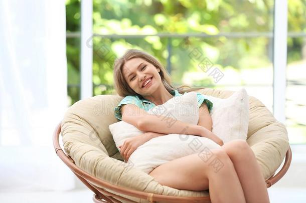 年幼的女人拥抱枕头采用舒适的扶手椅