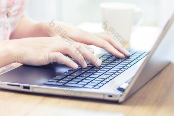 女人一次在书桌和打字向便携式电脑键盘