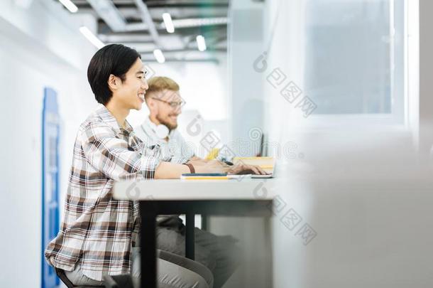 欢乐的人微笑的在期间工作的向便携式电脑采用co工作的空间