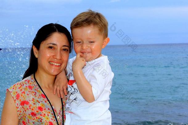 母亲和她年幼的儿子,向指已提到的人海滩在日落.