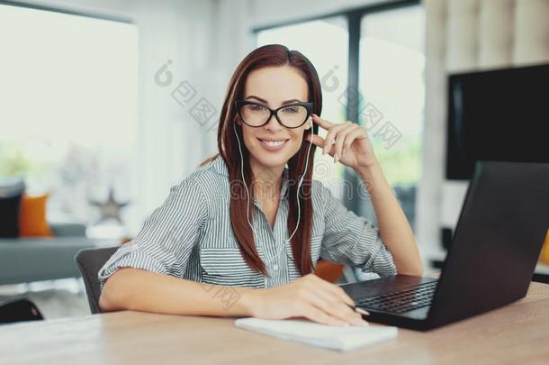 年幼的聪明的勤奋的女人露出牙齿的微笑在便携式电脑