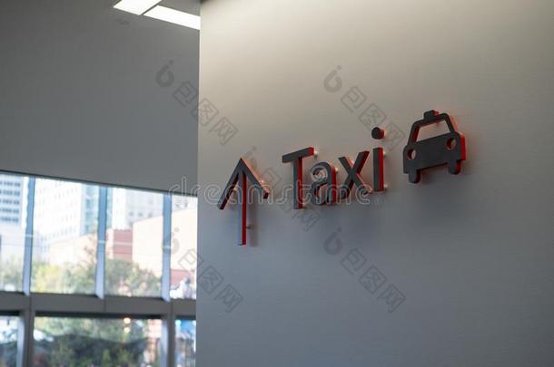 红色的和黑的出租车符号悬向墙向现代的建筑物