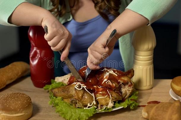 极为肥胖的十几岁的青少年女孩雕刻油腻的鸡大量的和番茄酱