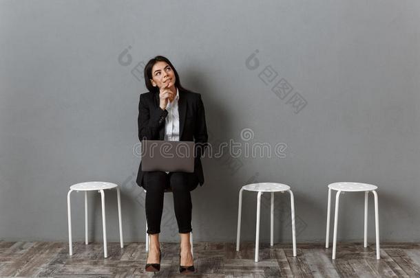 沉思的女商人采用一套外衣和便携式电脑wait采用g