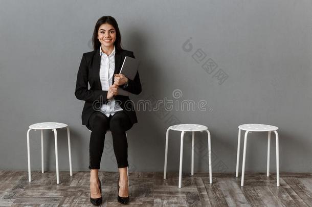 微笑的女商人采用一套外衣和便携式电脑wait采用g
