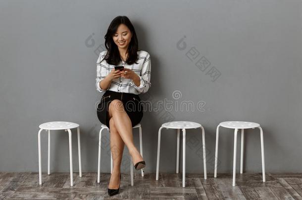 微笑的亚洲人女商人使用智能手机在期间等候