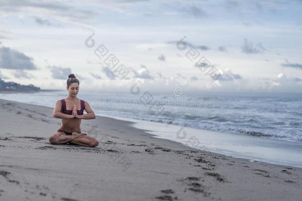 镇定的年幼的女人开业的瑜伽采用莲花使摆姿势