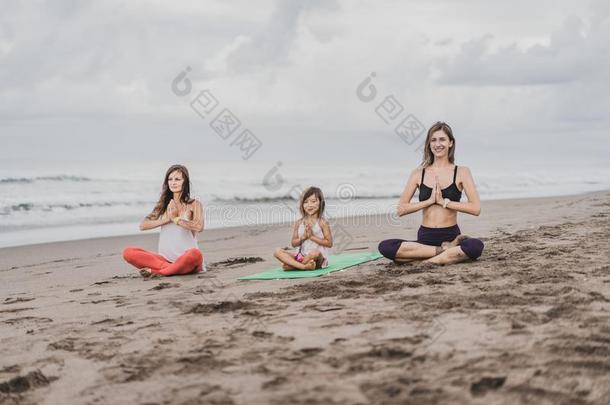 两个年幼的女人和小的小孩<strong>开业</strong>的瑜伽向海岸向