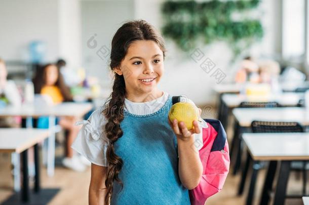 微笑的小的女学生和绿色的苹果
