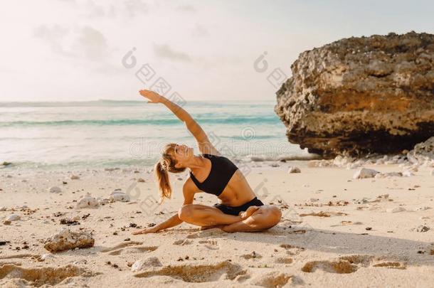 年幼的有魅力的女人开业的瑜伽向指已提到的人洋海滩.