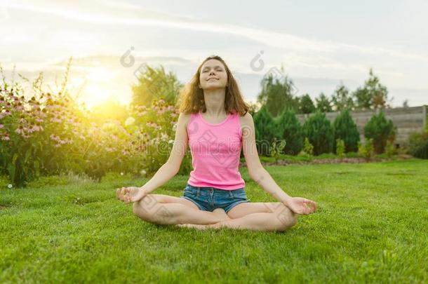 年幼的十几岁的女孩开业的瑜伽,深思向一夏太阳