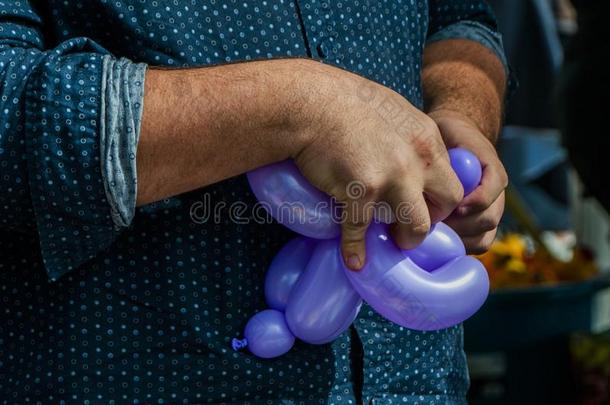 气球雕刻家创造一紫色的气球雕刻