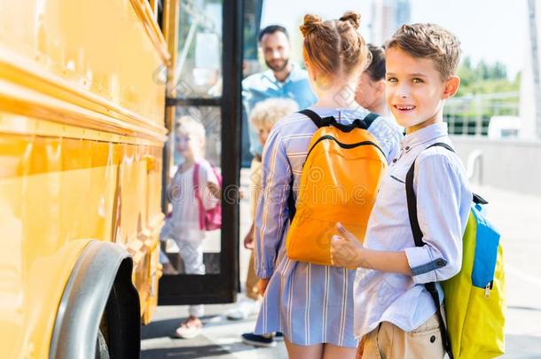 微笑的小的男生进入学校公共汽车和同学whiteiron白铁
