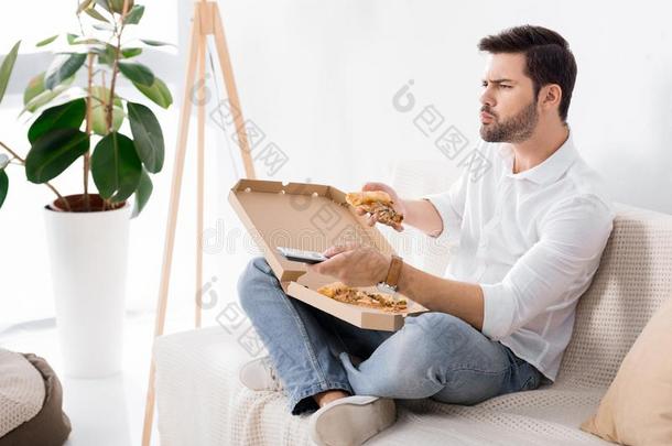 男人吃意大利薄饼在期间观察television电视机单独的