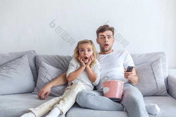 害怕的父亲和女儿观察疤痕斑斑的电影