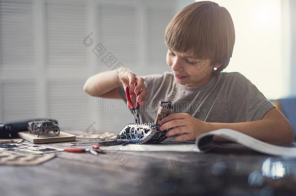 积极的男孩微笑的在期间使用钳子采用他的使工作和机械
