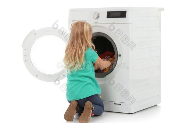漂亮的小的女孩有样子的进入中洗涤机器和洗衣店