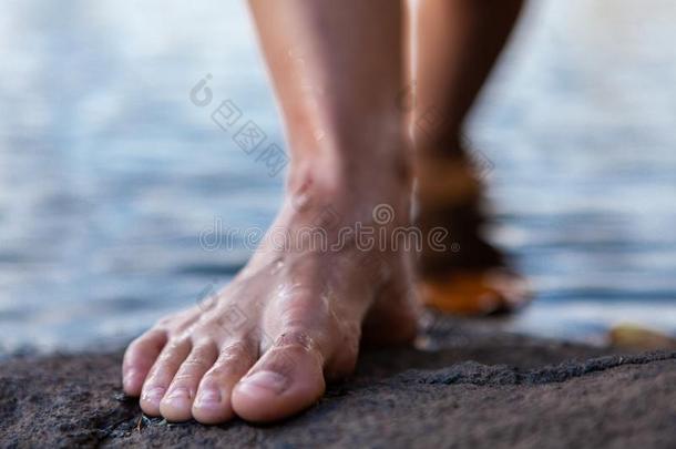 年幼的女人步行出局关于指已提到的人水光秃秃的脚向一岩石