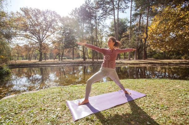 女人开业的瑜伽练习在城市公园采用指已提到的人Morn采用g