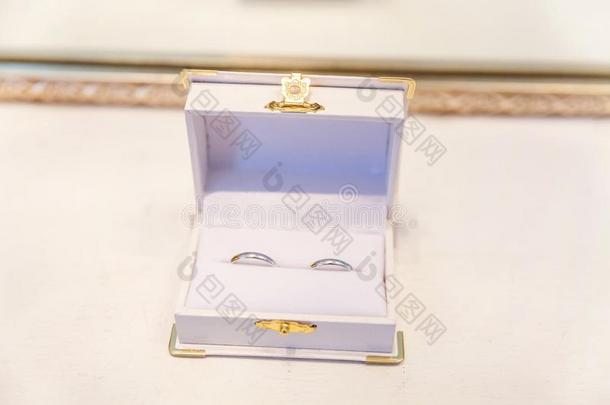 两个美丽的婚礼戒指向白色的珠宝盒向光后面