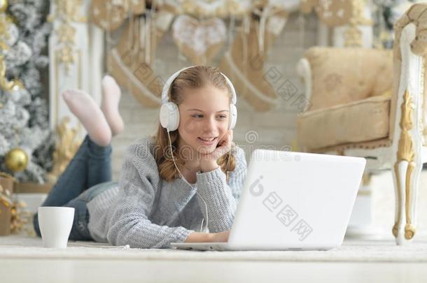 肖像关于十几岁的女孩和耳机使用便携式电脑