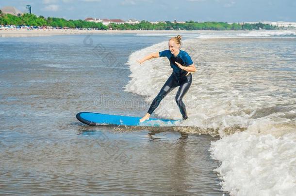 快乐的年幼的女人新手冲浪运动员和蓝色海浪有乐趣向subjectmatterarea主题区