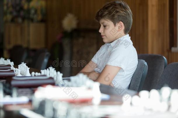 漂亮的,聪明的,11年老的男孩采用白色的衬衫坐采用指已提到的人班级