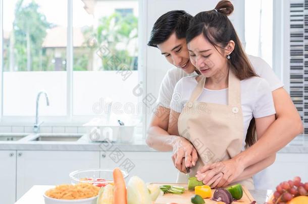 亚洲人一对烹饪术和限幅蔬菜采用厨房同时