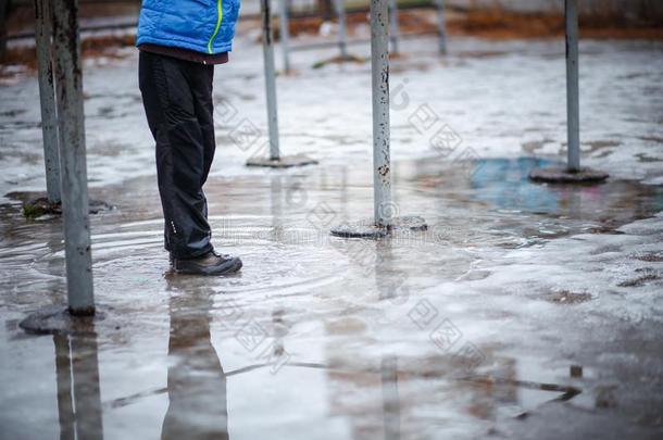 一小孩采用<strong>雪地靴</strong>擦靴人是（be的三单形式st一nd采用g采用一水坑关于融化埃尔维阵风