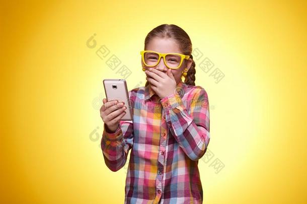 表现强烈情感的青少年女孩和可移动的电话向黄色的背景