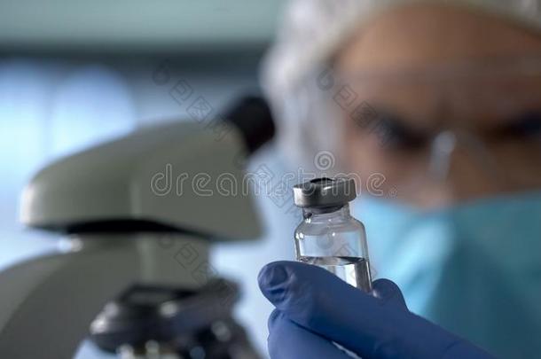 科学家出行向检查注射瓶子和新的疫苗在下面