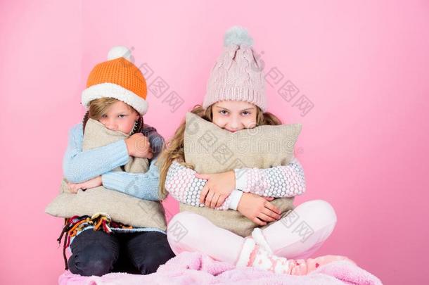 兄弟穿着冬暖和的帽子坐向粉红色的背景.孩子们
